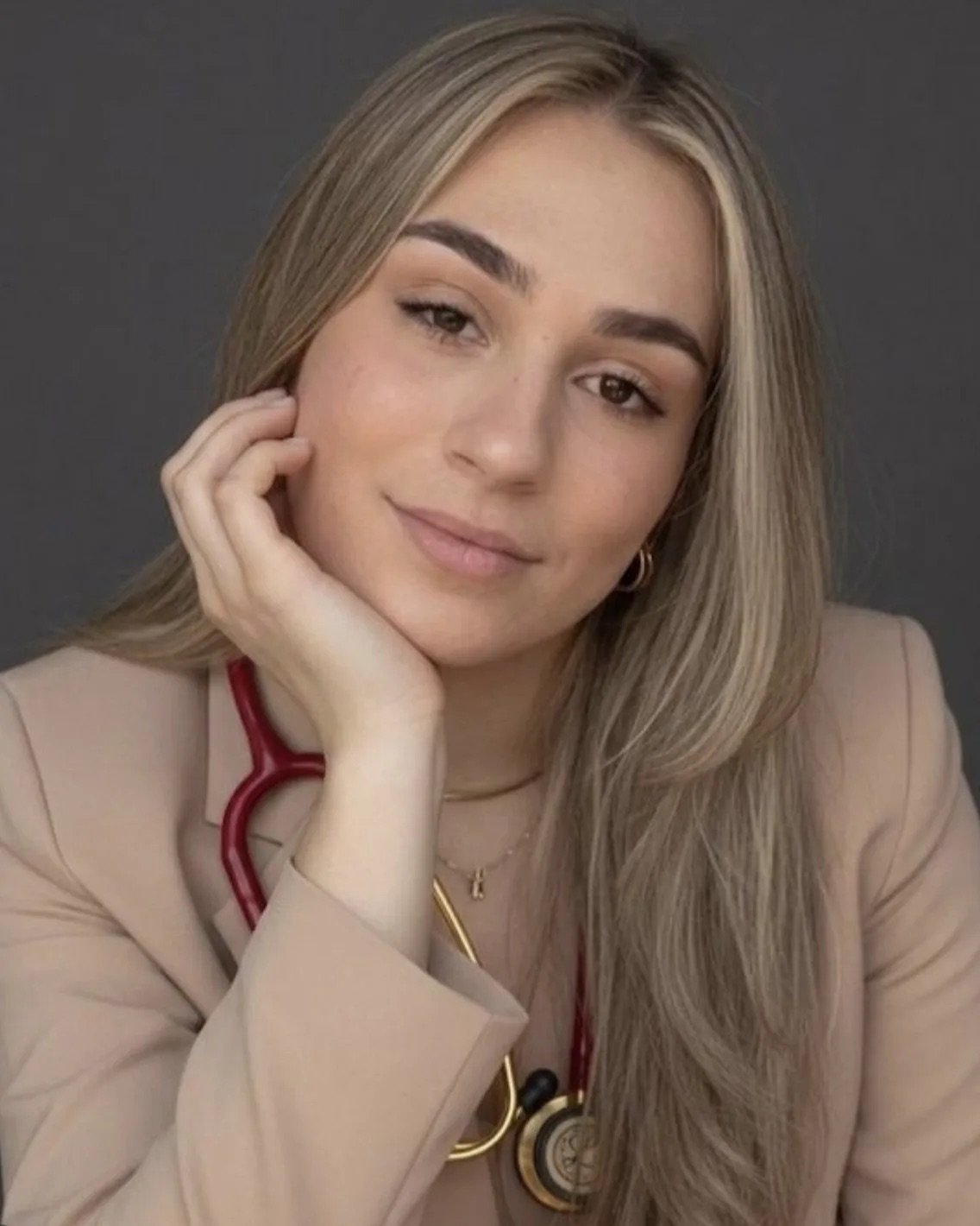 Retrato de Aline Pera com blazer bege e estetoscópio